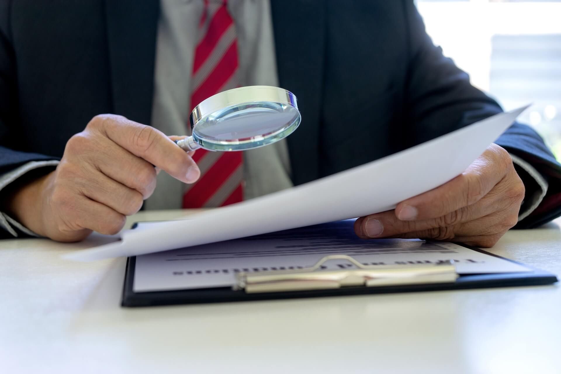 Lawyer or judge use magnifier glass look to the paper for inspection examination to the law case